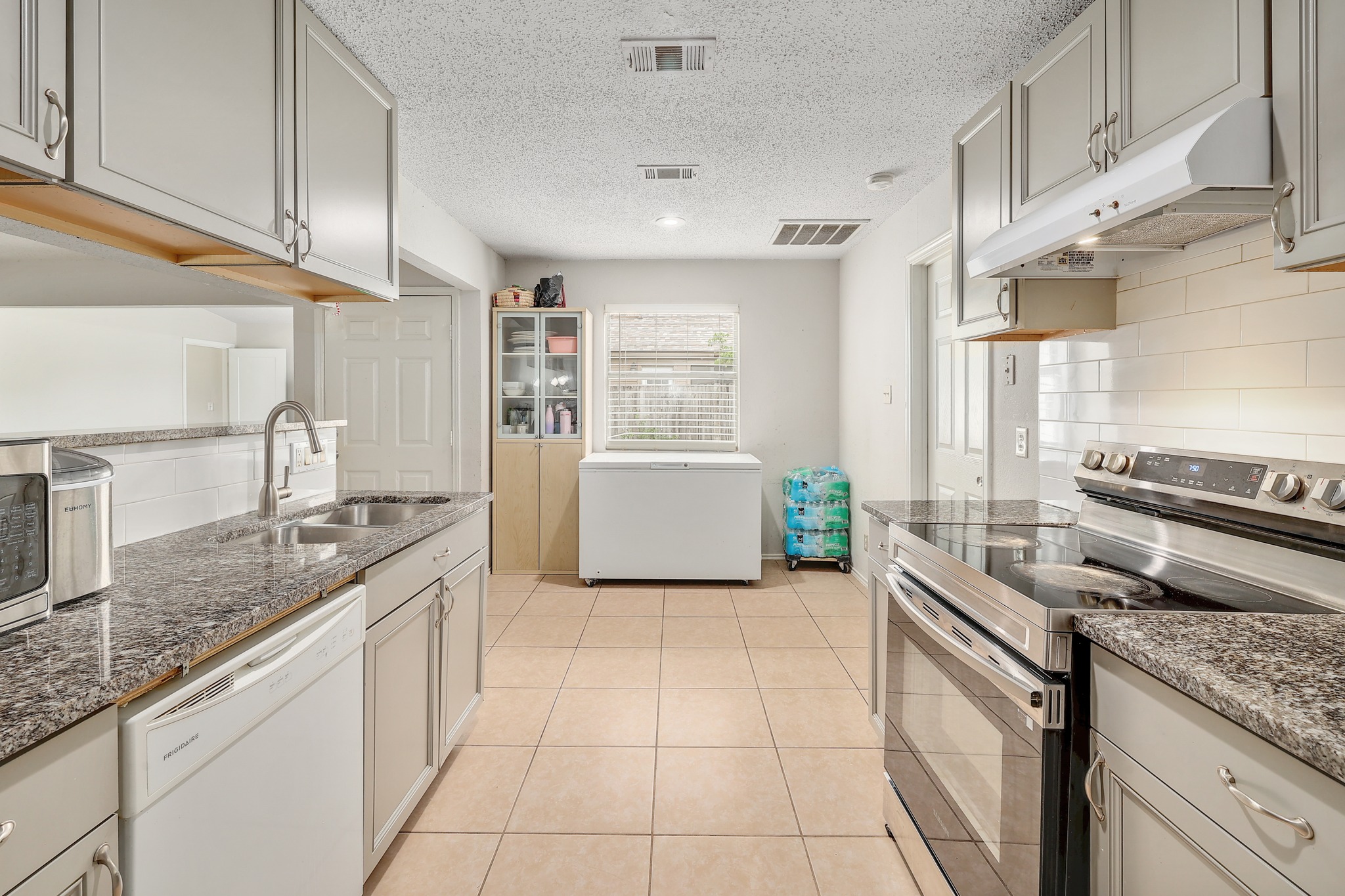 9901 Parliament House Road Austin, TX 78729 - Photo 22 of 40 Kitchen featuring stainless steel electric range oven, backsplash, dishwasher, a textured ceiling, and light tile patterned floors