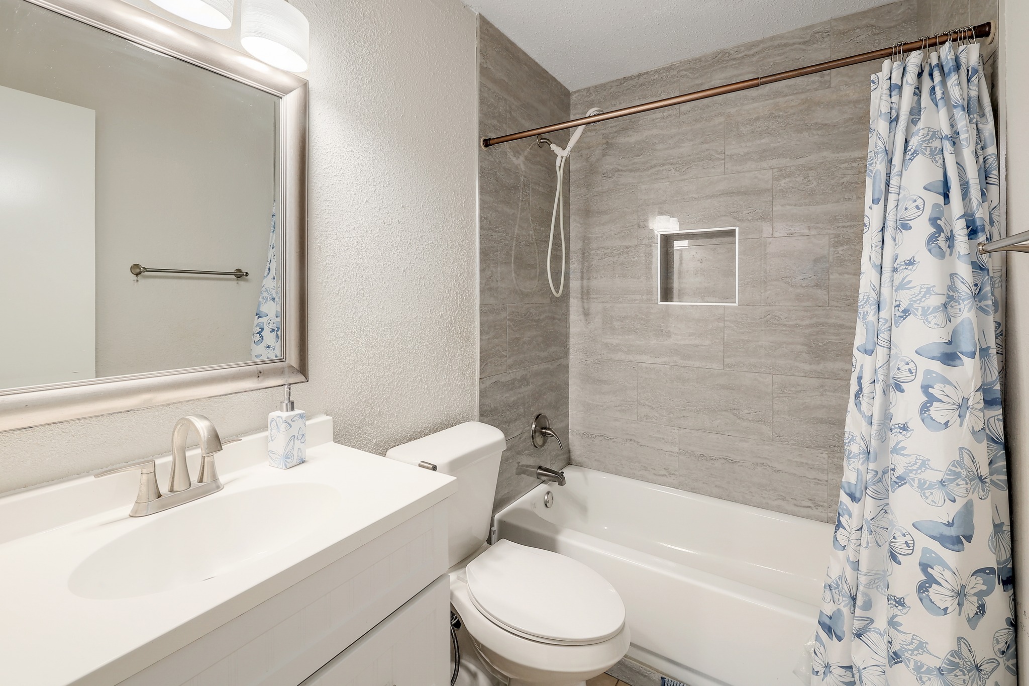 9901 Parliament House Road Austin, TX 78729 - Photo 26 of 40 Bathroom featuring a textured wall, vanity, and shower / bathtub combination with curtain