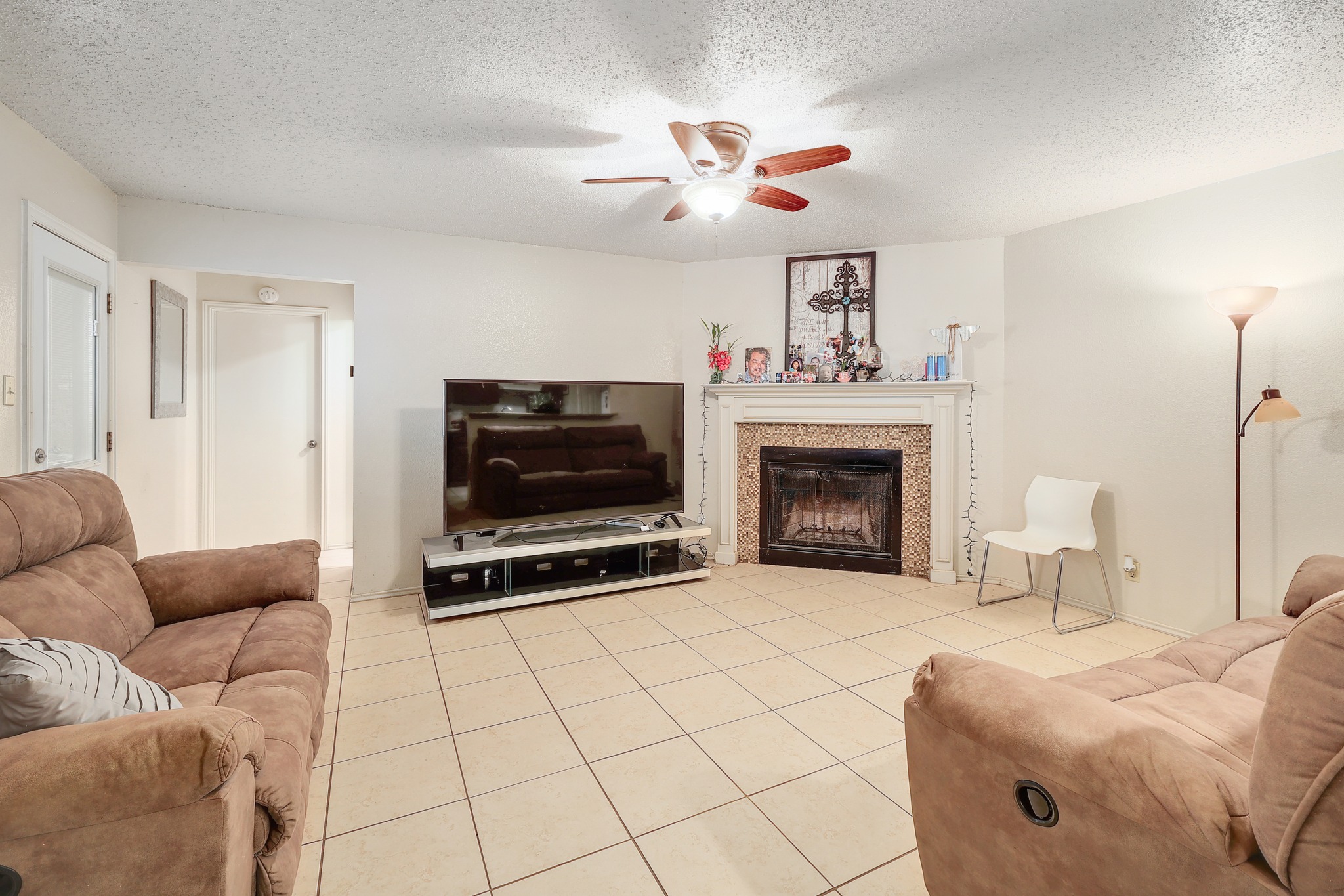9901 Parliament House Road Austin, TX 78729 - Photo 5 of 40 Living room with a textured ceiling, light tile patterned floors, ceiling fan, and a fireplace