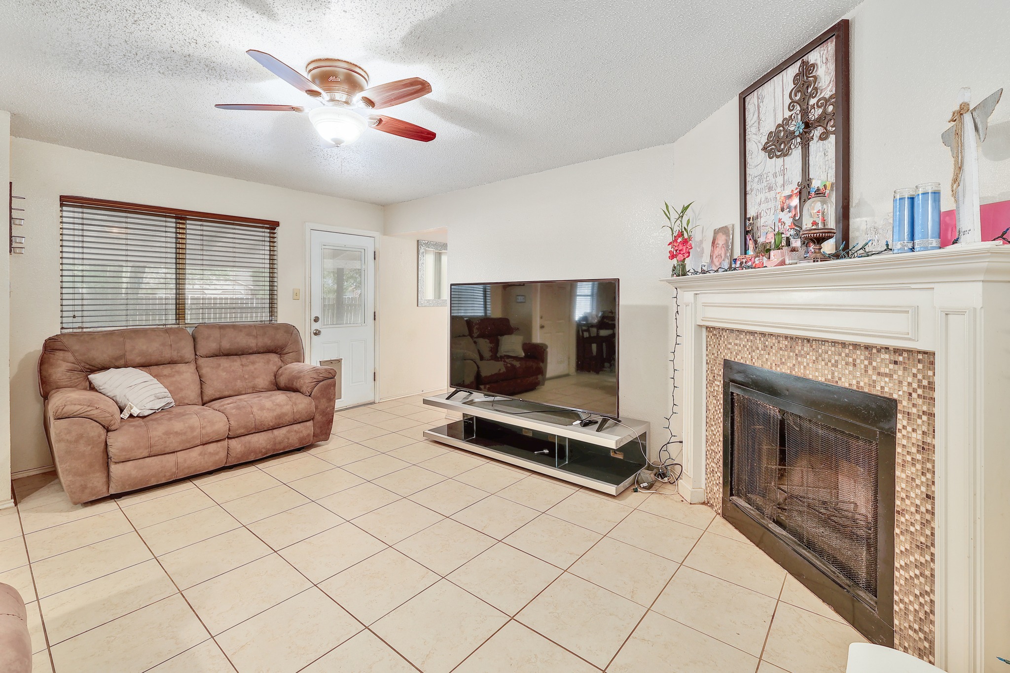 9901 Parliament House Road Austin, TX 78729 - Photo 6 of 40 Living area with a textured ceiling, light tile patterned flooring, ceiling fan, and a tile fireplace