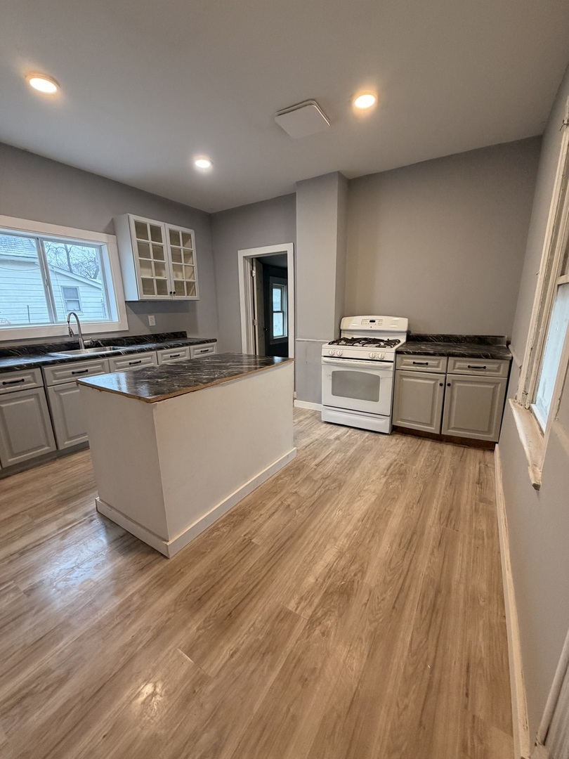 1024 South Warren Street Peoria, IL 61605 - Photo 2 of 14 a kitchen with granite countertop a stove and a wooden floors