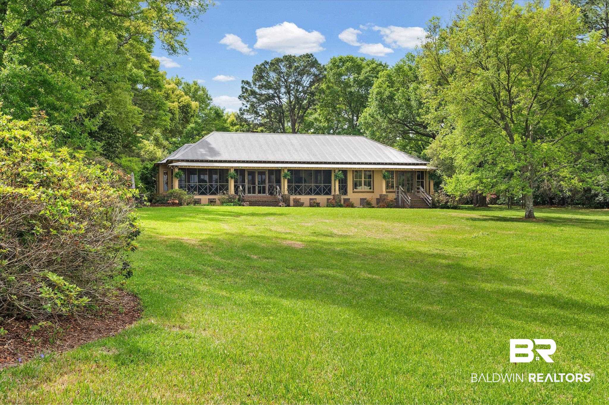 2300 Burgett Road Mobile, AL 36605 - Photo 36 of 40 View of front facade with a porch, a front yard, a metal roof, and view of scattered trees