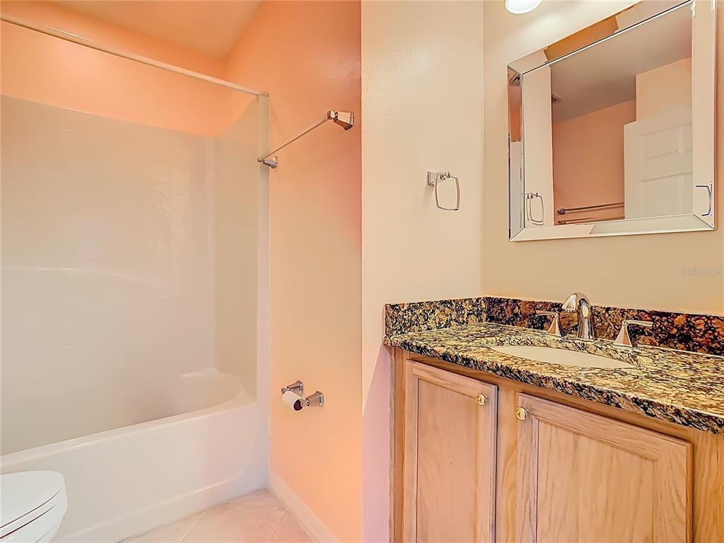 121 Rialto Road Poinciana, FL 34759 - Photo 29 of 68 a bathroom with a granite countertop sink a mirror and a bathtub