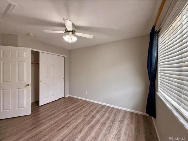an empty room with wooden floor ceiling fan and windows