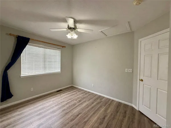 a view of empty room with wooden floor and fan