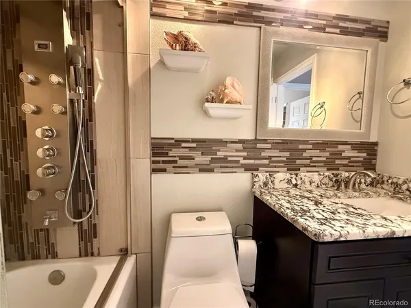 a bathroom with a granite countertop sink a toilet and shower