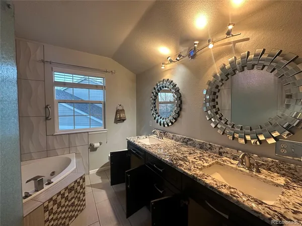 a bathroom with a granite countertop sink a large mirror and bathtub