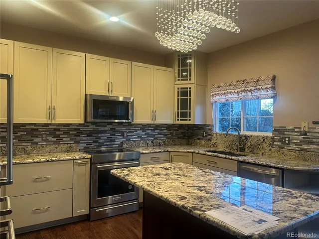 a kitchen with kitchen island granite countertop a sink a counter space appliances and cabinets