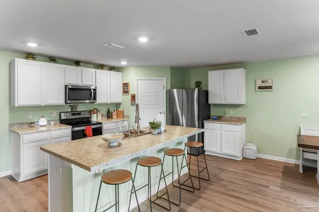 a kitchen with stainless steel appliances granite countertop a stove a refrigerator a sink a dining table and chairs