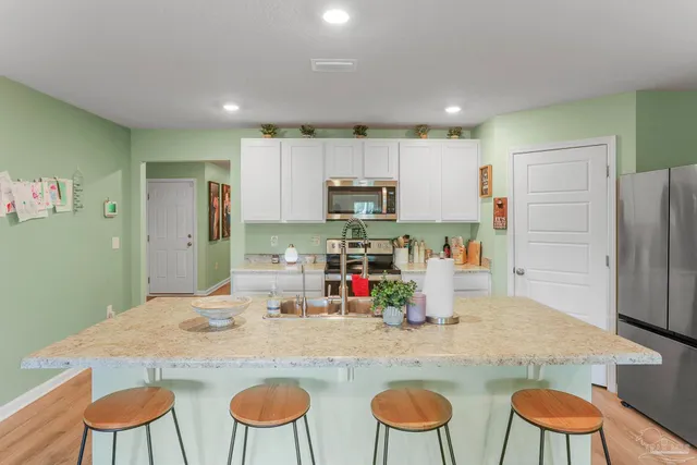 a kitchen with stainless steel appliances granite countertop a dining table chairs and refrigerator