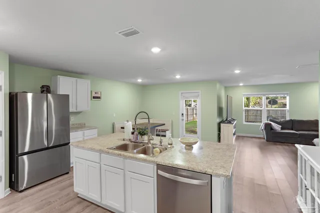 a kitchen with stainless steel appliances granite countertop a sink a refrigerator and couches