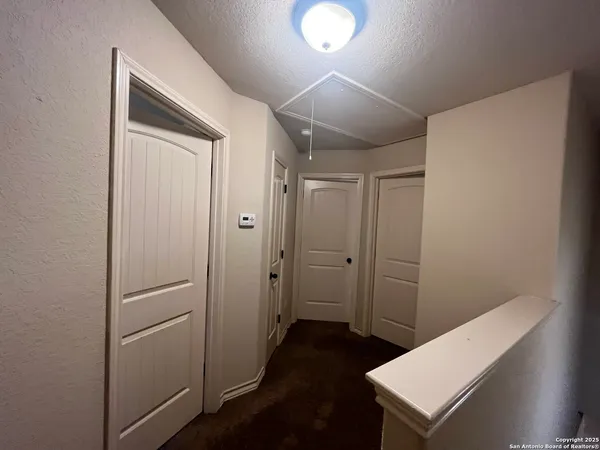 a view of an empty room with window and chandelier fan
