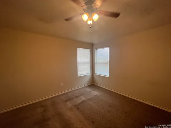an empty room with a fan & a window