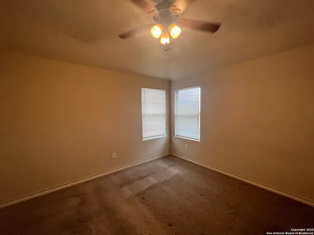 an empty room with a fan & a window