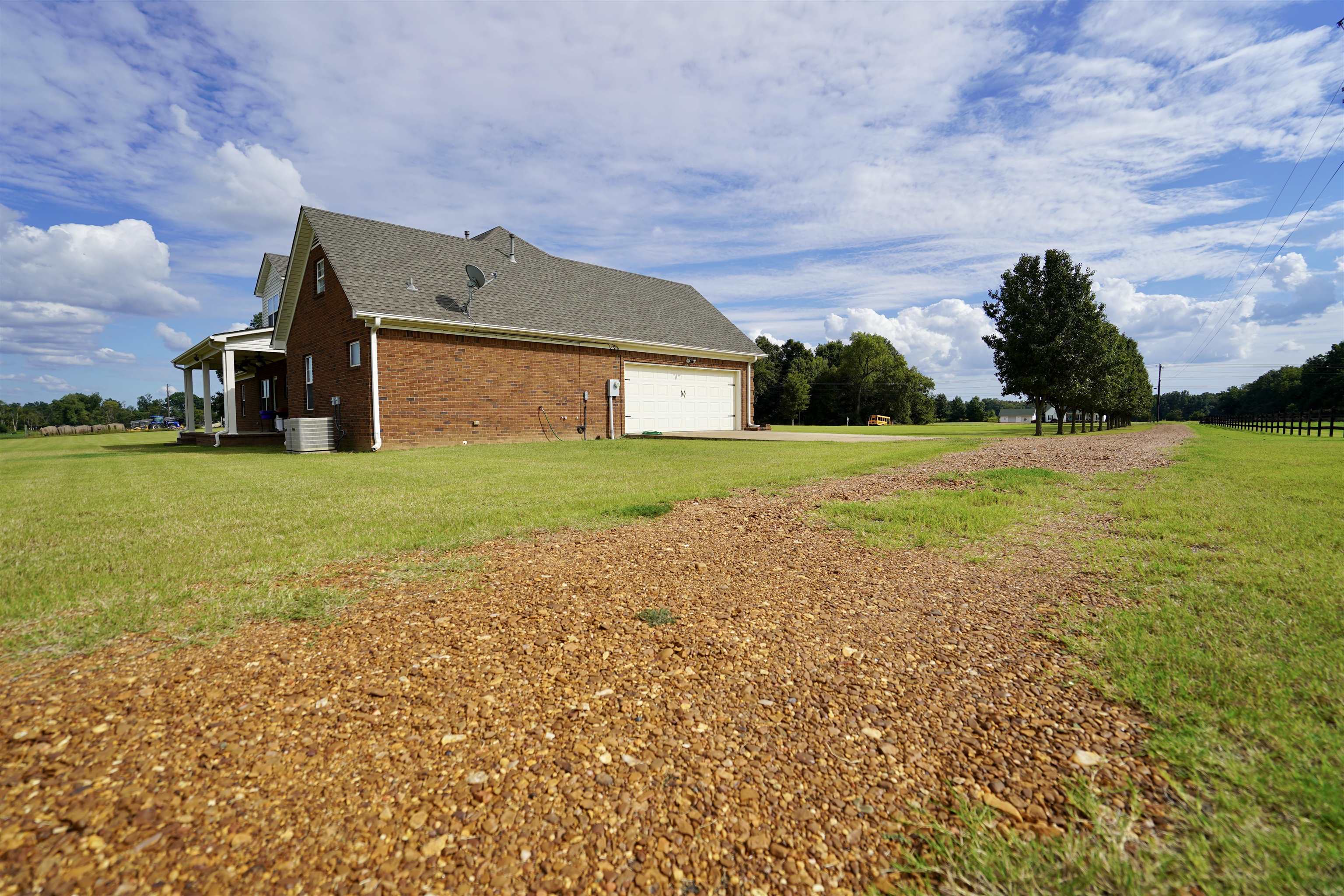 4556 Gainsville Road Mason, TN 38049 - Photo 7 of 33 View of home's exterior featuring a yard, a garage, and central AC