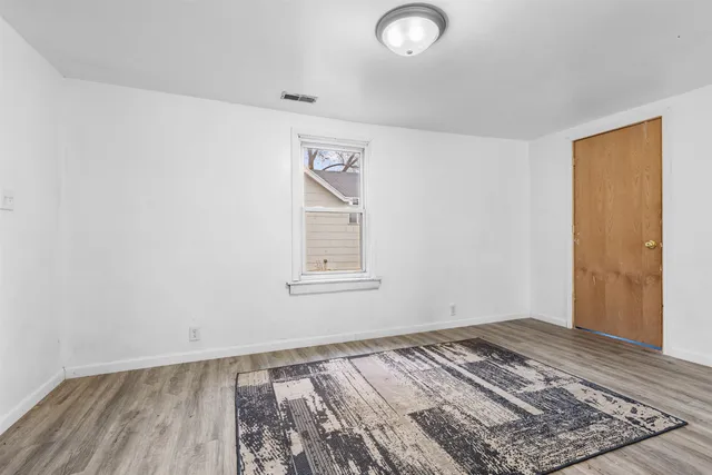 an empty room with wooden floor and window