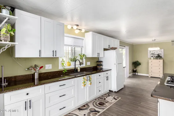 a kitchen with granite countertop a sink a stove a refrigerator and white cabinets