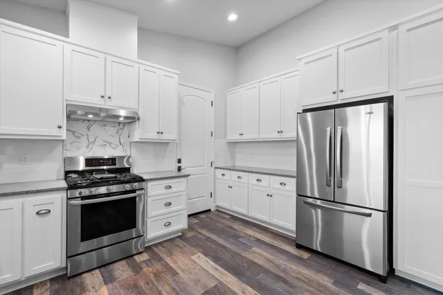 a kitchen with cabinets stainless steel appliances and wooden floor