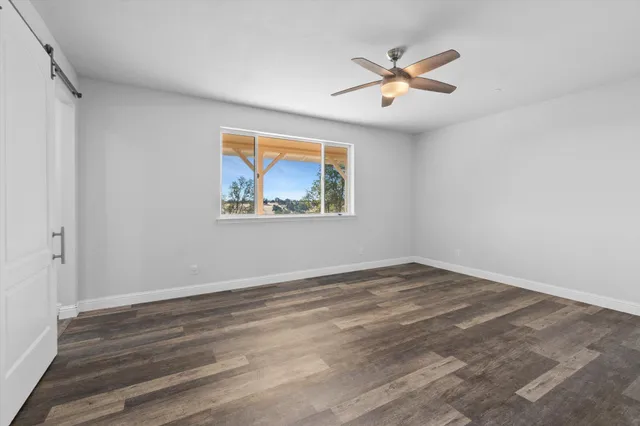 an empty room with wooden floor and ceiling fan