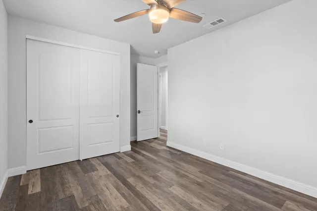 an empty room with wooden floor fan and window