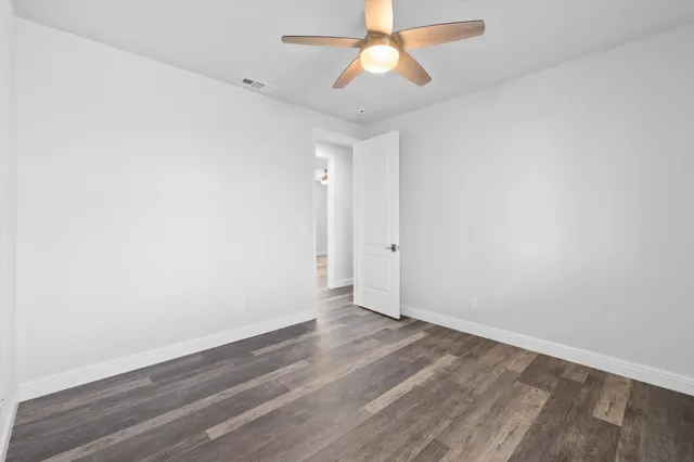 an empty room with wooden floor and ceiling fan