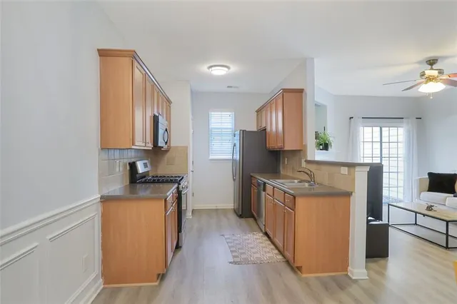 a kitchen with stainless steel appliances granite countertop a stove top oven a sink dishwasher and a refrigerator