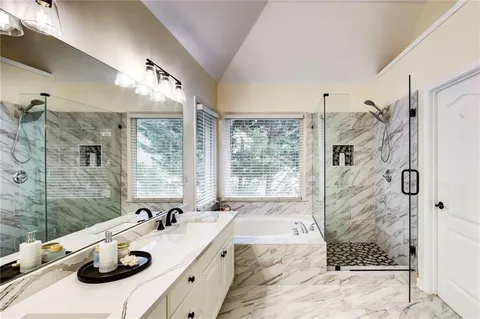 a bathroom with a double vanity sink and mirror with bathtub