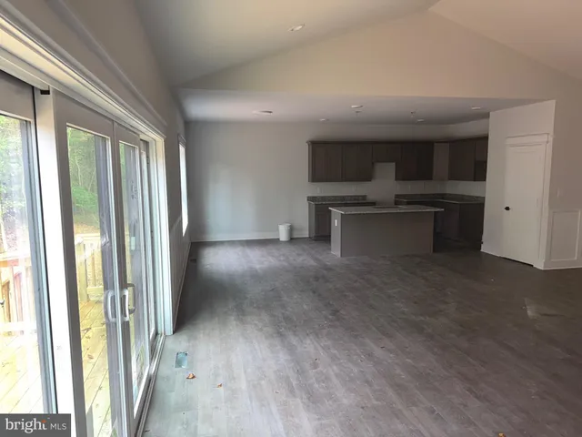 a view of empty room with kitchen and window