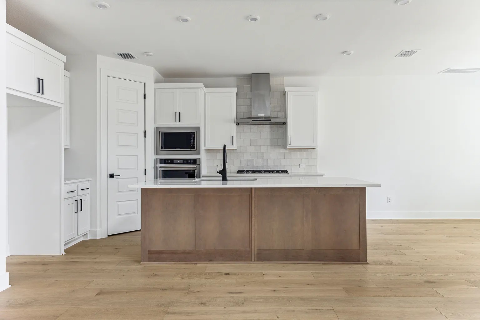 1909 Varese Path Leander, TX 78641 - Photo 12 of 40 A contemporary kitchen features an island with a sink, white cabinetry, and stainless steel appliances.