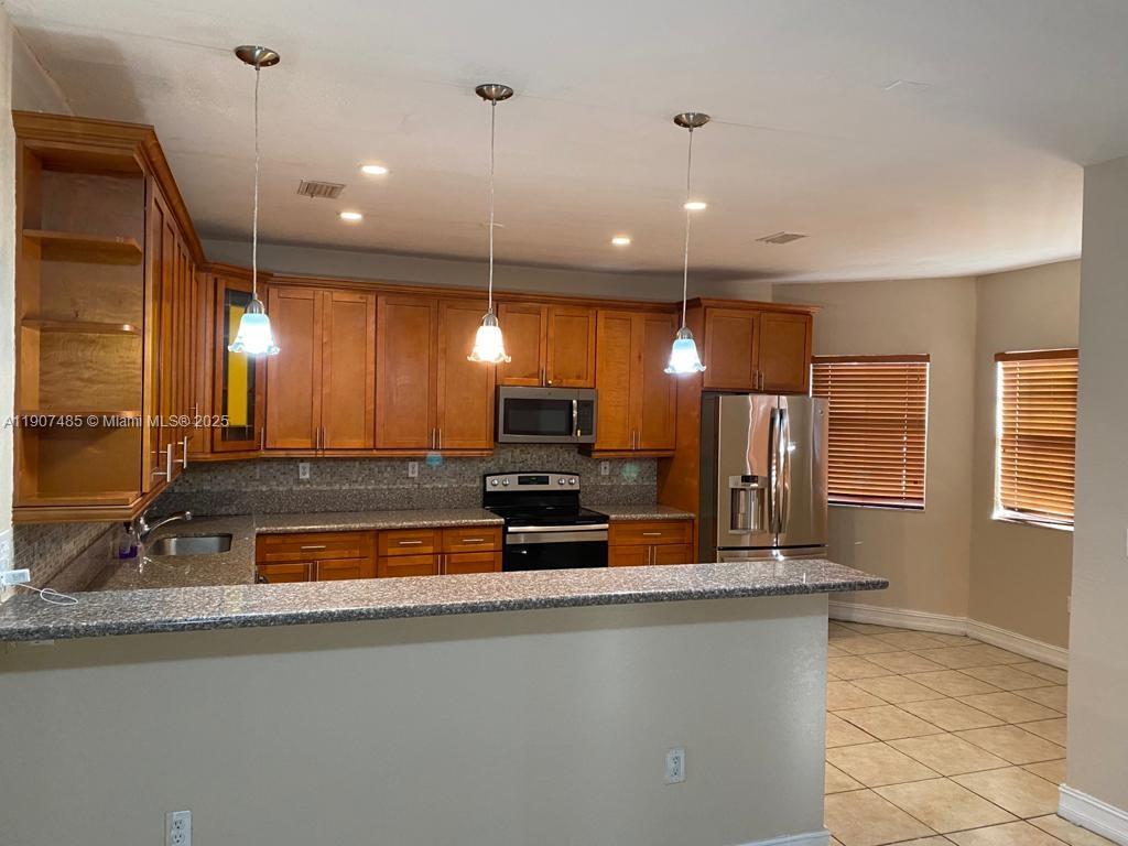 13426 Southwest 177th Terrace Miami, FL 33177 - Photo 12 of 36 a large kitchen with a large counter top a sink a window and stainless steel appliances