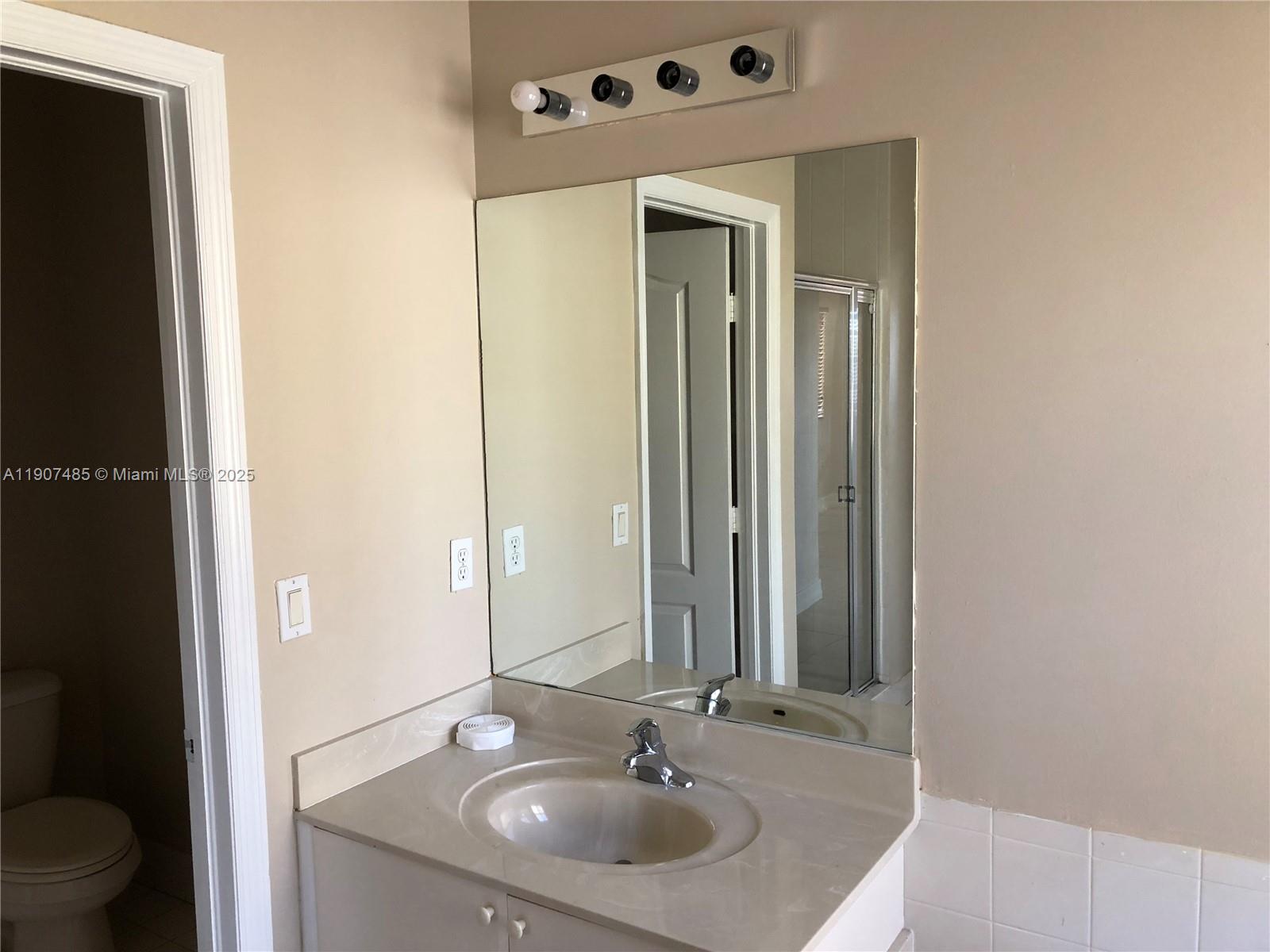 13426 Southwest 177th Terrace Miami, FL 33177 - Photo 29 of 36 a bathroom with a sink and a mirror with toilet