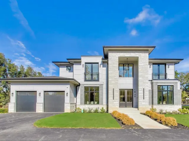 a view of a brick house with a yard plants and large tree