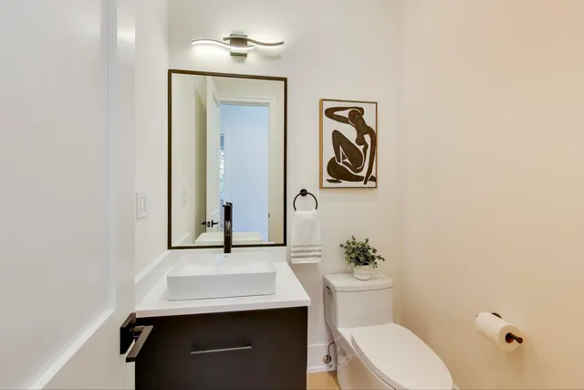 a bathroom with a granite countertop sink a toilet a mirror and shower