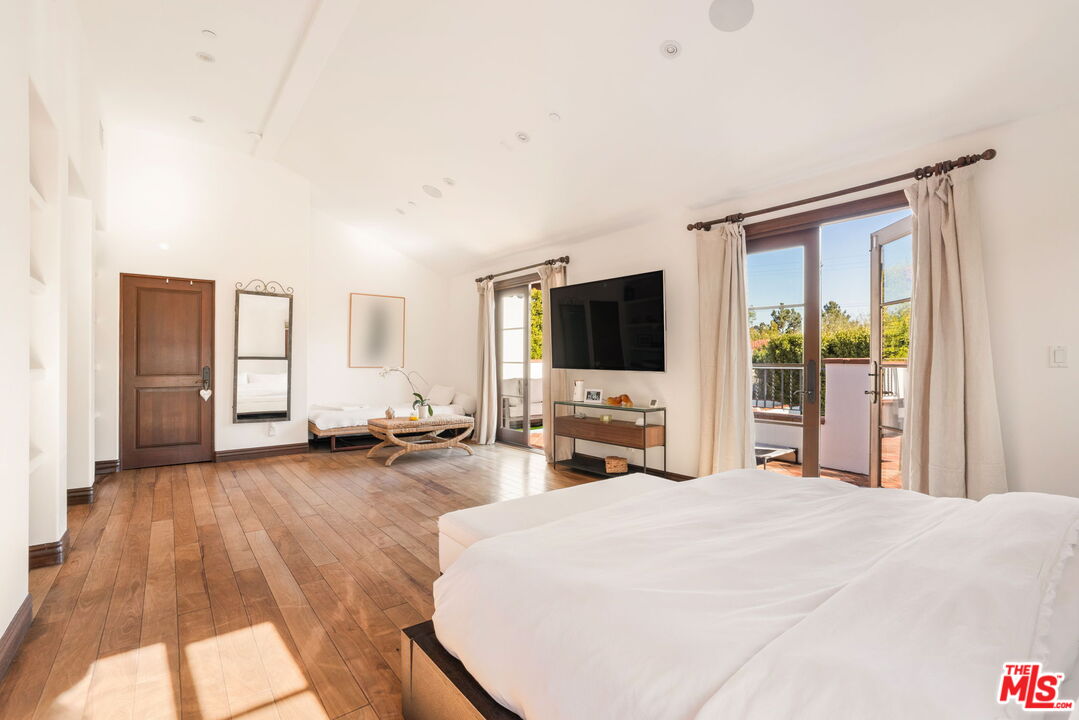 604 Alta Drive Beverly Hills, CA 90210 - Photo 10 of 21 a large bedroom with a bed and a flat tv screen on wall