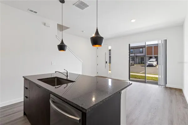 a kitchen with stainless steel appliances granite countertop a sink a oven and a wooden floor