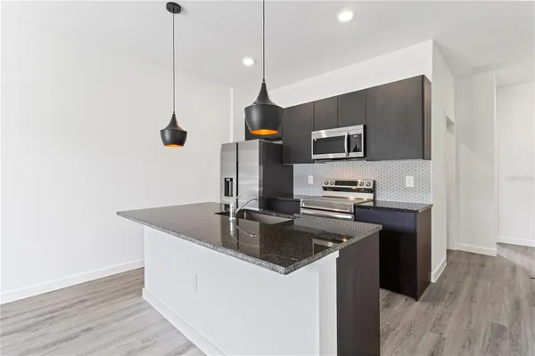 a kitchen with stainless steel appliances granite countertop a sink a microwave and wooden floors
