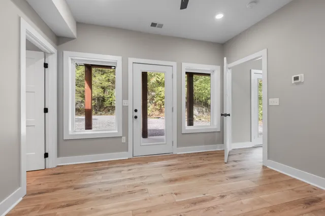 a view of an empty room with wooden floor and a window
