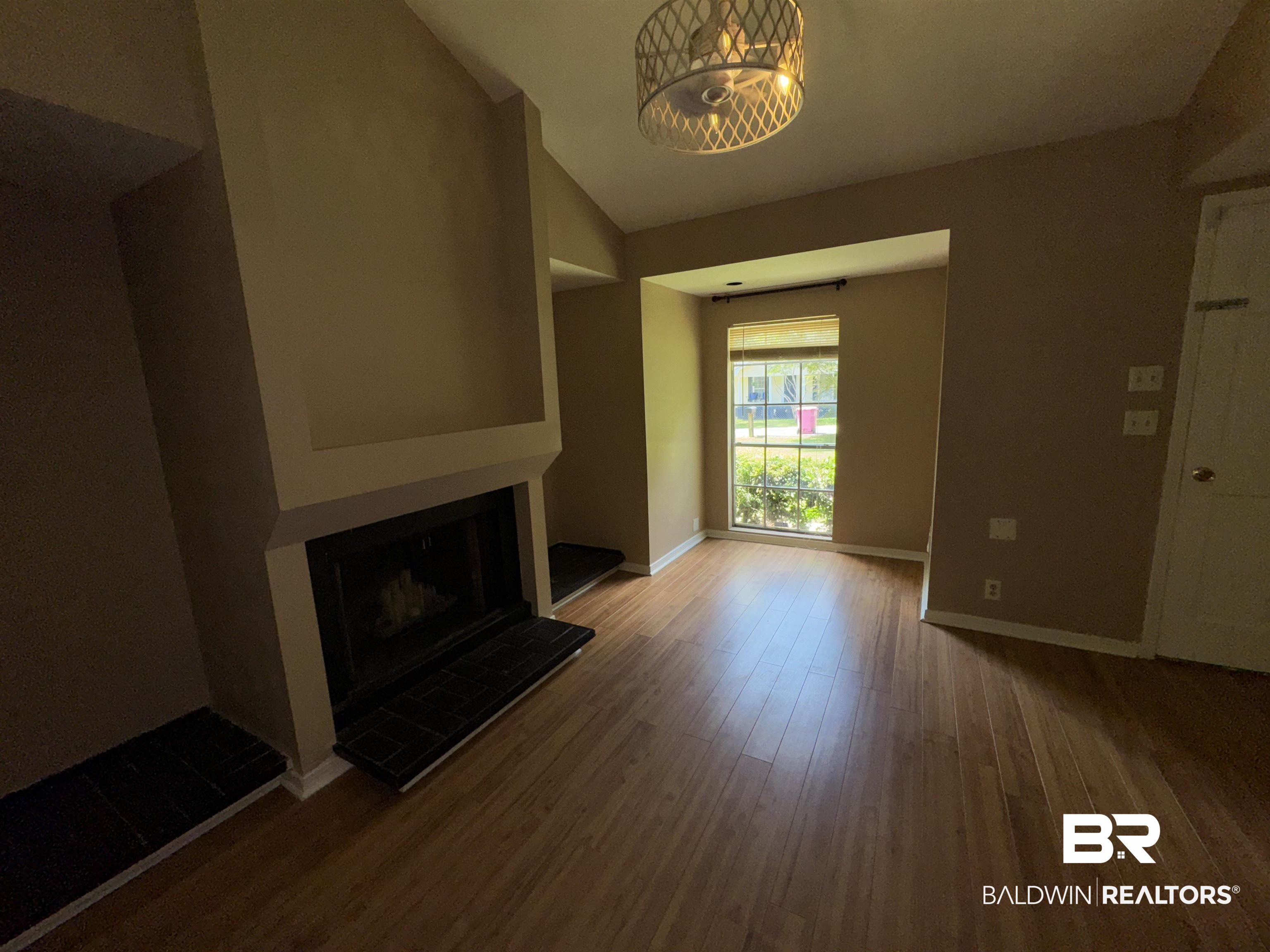 8070 Middle Ring Road Mobile, AL 36619 - Photo 7 of 26 Unfurnished living room with a fireplace with raised hearth, wood finished floors, a chandelier, and lofted ceiling