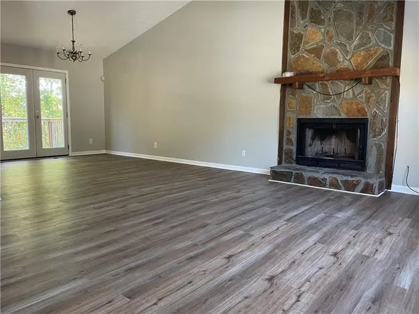 an empty room with wooden floor fireplace cabinet and windows