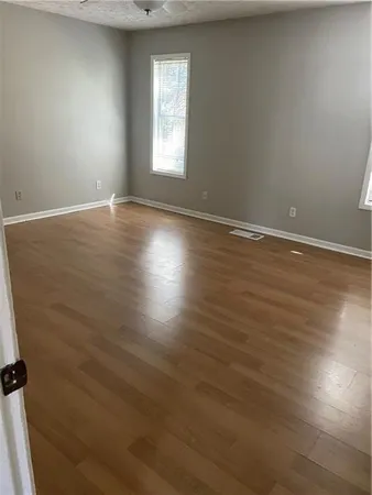 an empty room with wooden floor and windows