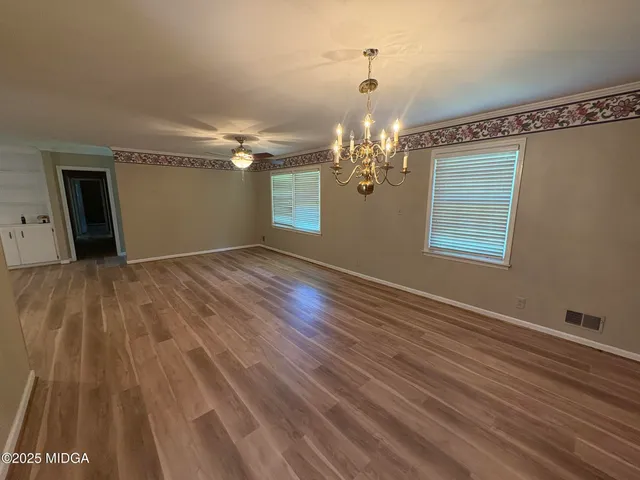 a view of a room with wooden floor chandelier and window