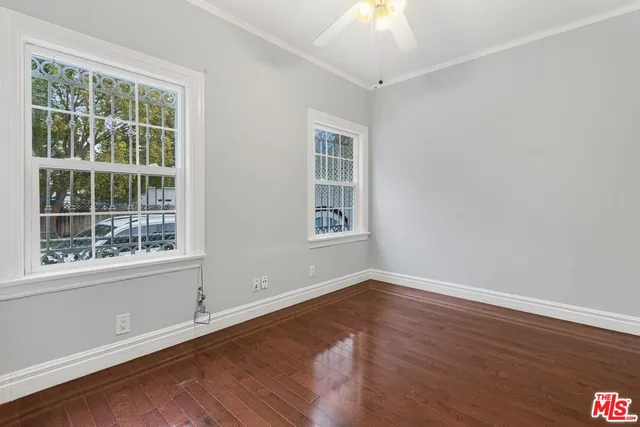 a view of an empty room with wooden floor and a window