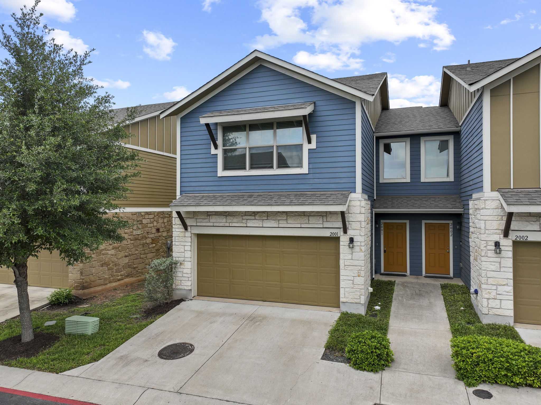 The property features blue siding, stone accents, and a brown garage door