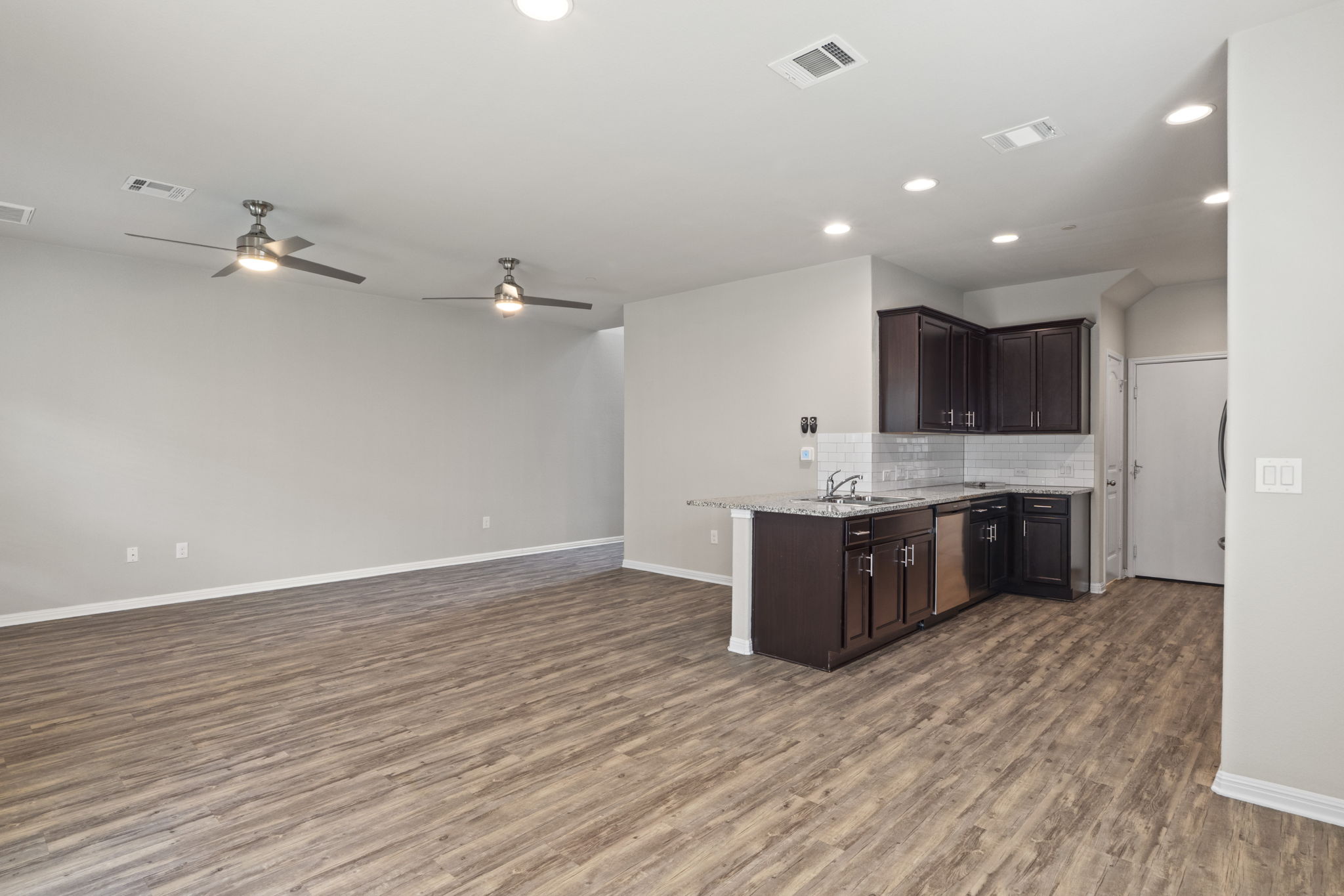 516 East Slaughter Lane, Unit 2001 Austin, TX 78744 - Photo 11 of 31 Open concept living area featuring hardwood style flooring, recessed lighting, and a kitchen with dark cabinetry, granite countertops, and a subway tile backsplash