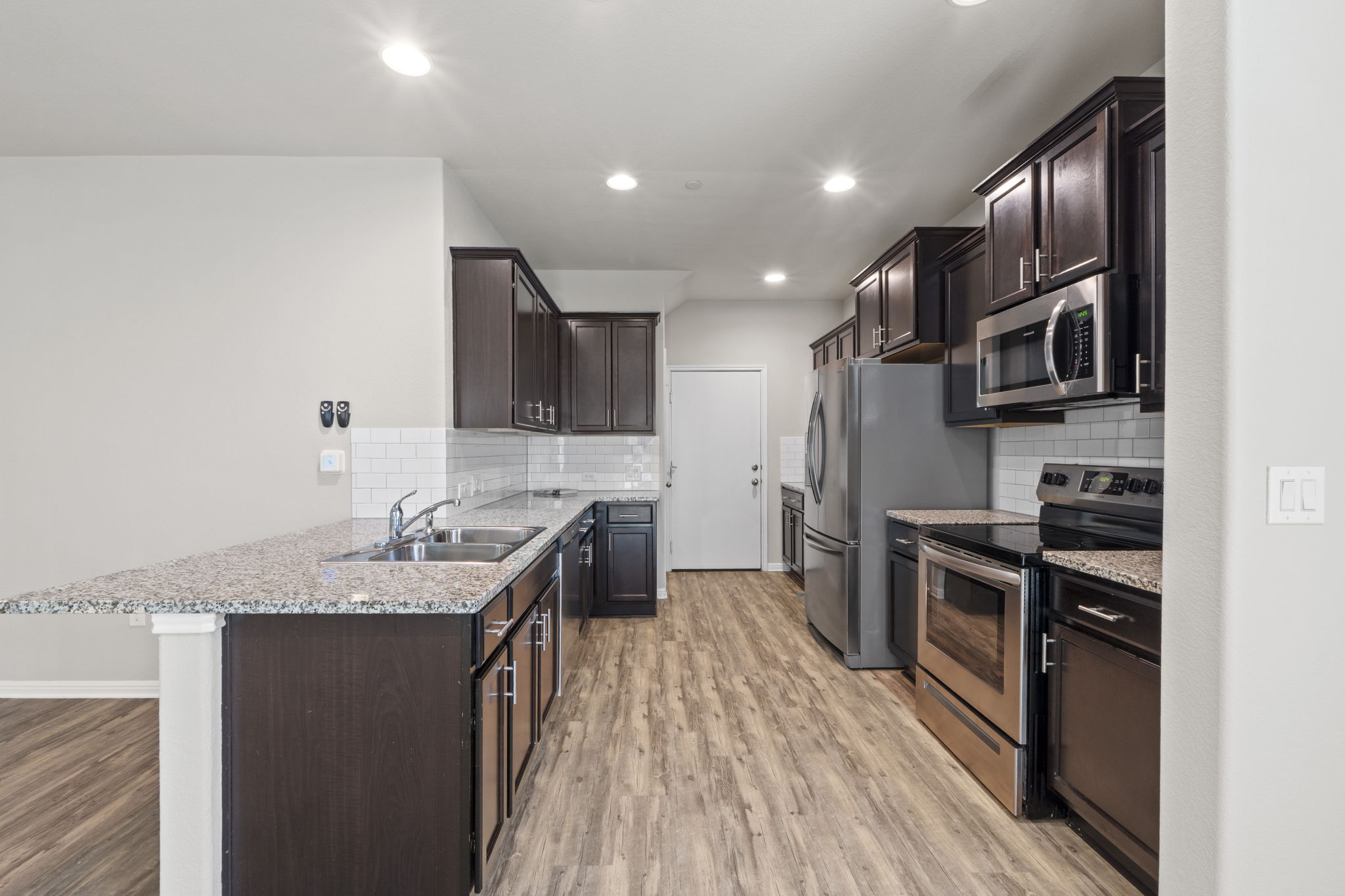 516 East Slaughter Lane, Unit 2001 Austin, TX 78744 - Photo 16 of 31 The kitchen features dark wood cabinetry, granite countertops, stainless steel appliances, and a white subway tile backsplash