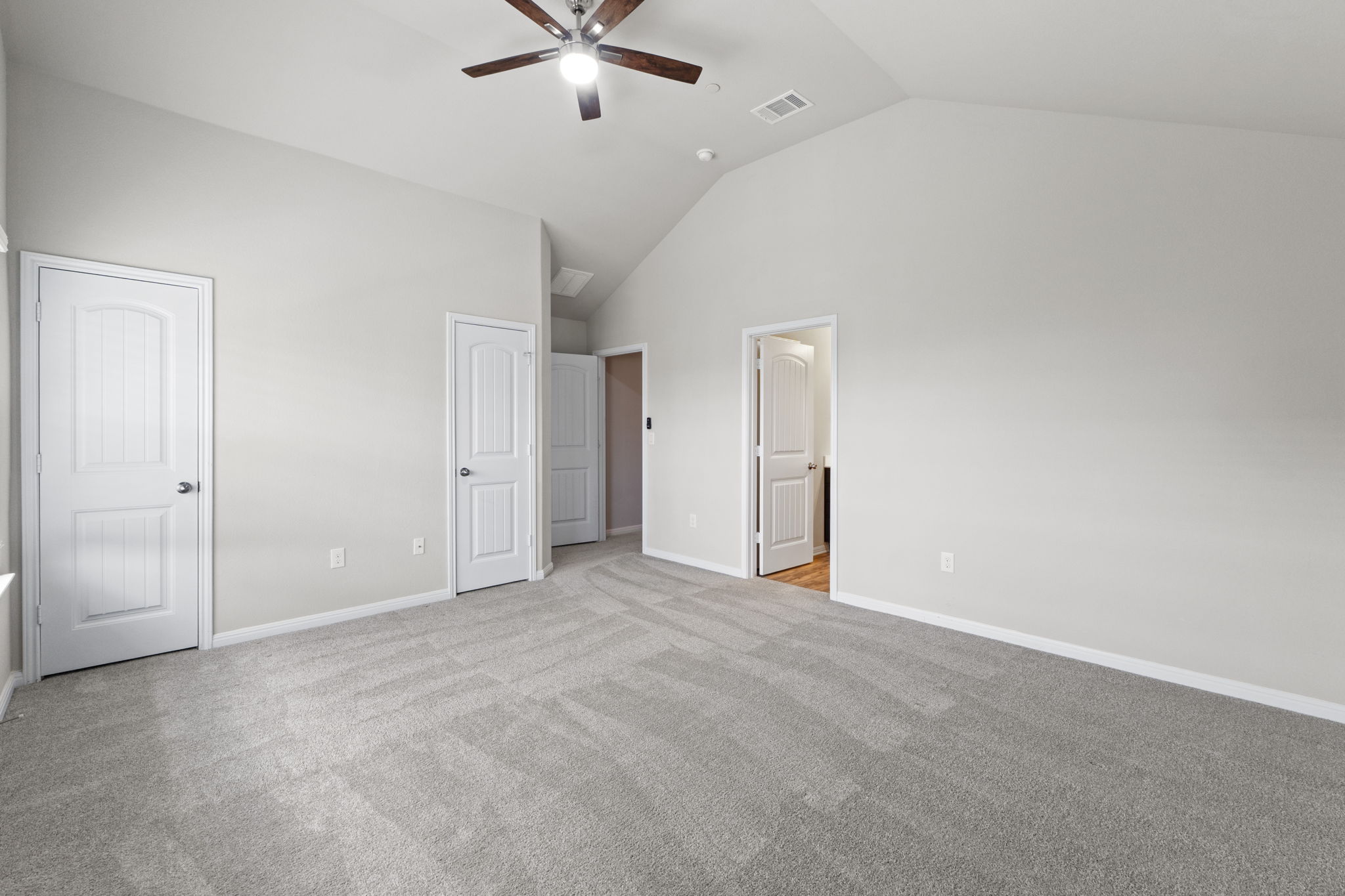 516 East Slaughter Lane, Unit 2001 Austin, TX 78744 - Photo 22 of 31 This room features a vaulted ceiling with a ceiling fan, light gray carpeting, and multiple white paneled doors