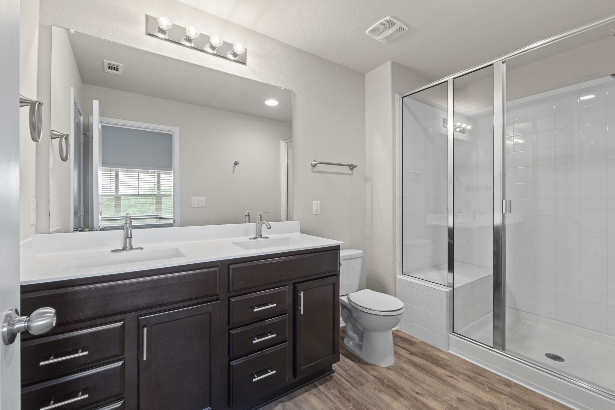 516 East Slaughter Lane, Unit 2001 Austin, TX 78744 - Photo 27 of 31 The bathroom features a double vanity with dark wood cabinetry, a large mirror, a toilet, and a spacious glass-enclosed shower