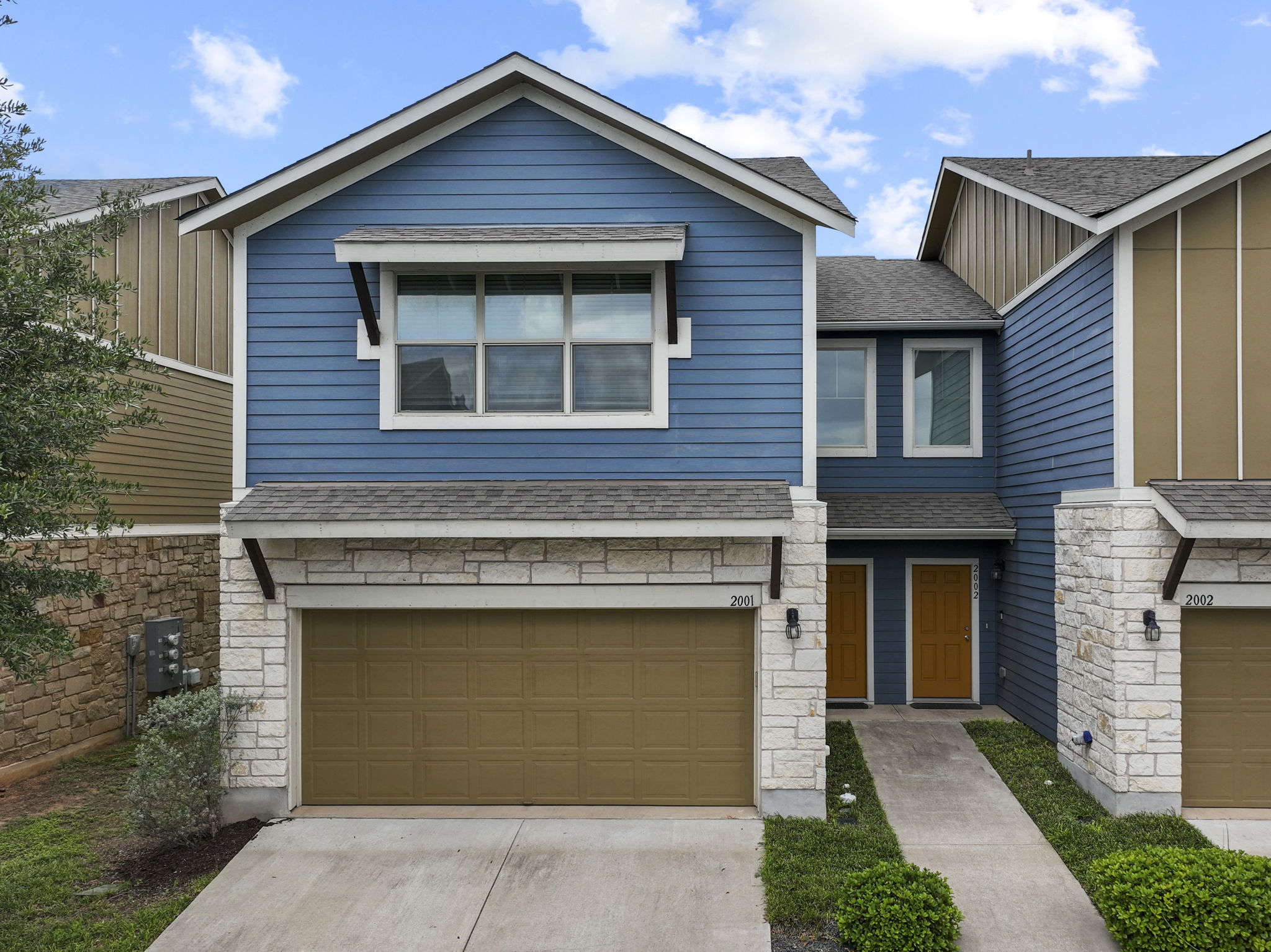 516 East Slaughter Lane, Unit 2001 Austin, TX 78744 - Photo 7 of 31 The property features a blue exterior with stone accents, a two-car garage, and a concrete driveway