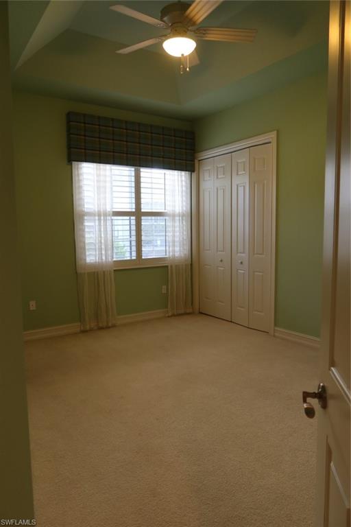 7168 Lemuria Circle, Unit 1701 Naples, FL 34109 - Photo 25 of 39 Recessed tray ceiling with ceiling fan, neutral carpet flooring, and bi-fold closet doors