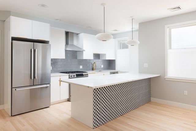 a kitchen with stainless steel appliances granite countertop a sink a stove a refrigerator and island with wooden floor